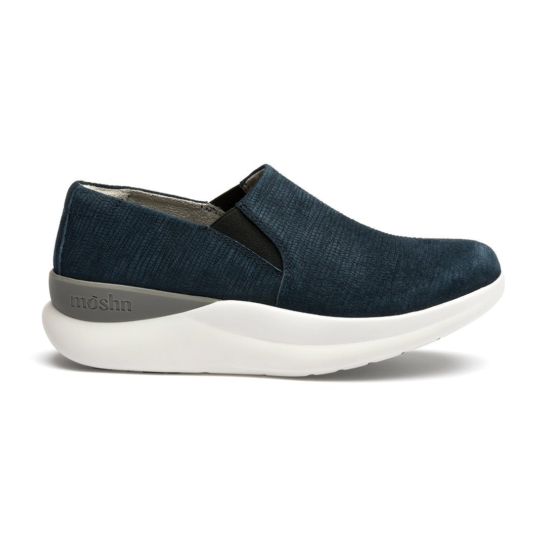 A pair of navy blue suede slip-on shoes with a white sole.